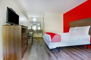 Une chambre d’hôtel avec un lit, une télévision, une commode et une salle de bain à l’arrière-plan.