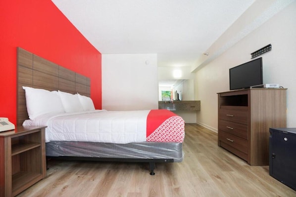 A hotel room with a bed, a TV, a wardrobe, and a desk with a phone. - Decatur GA | King Bed (Decatur GA)