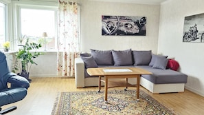 A living room with a sofa, a coffee table, a rug, and two wall-mounted pictures. - Apartment Near the Sea in Skärhamn | SE09178 (Skärhamn)