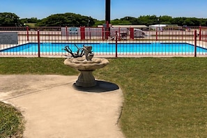 En swimmingpool med ett rött staket, en gångbana av betong och en dekorativ fontän.