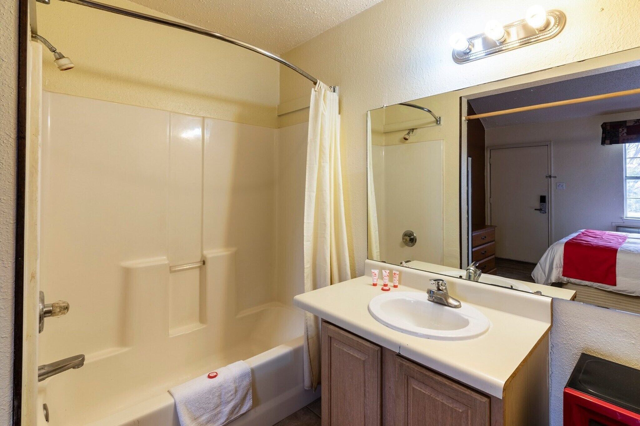 A bathroom with a bathtub, a sink, a mirror, and a shower curtain.