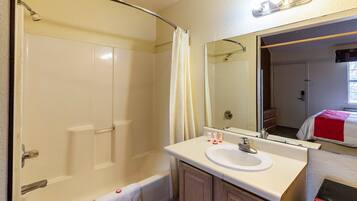 A bathroom with a bathtub, a sink, a mirror, and a shower curtain.