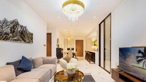 Ein modernes Wohnzimmer mit einer Couch, einem runden Couchtisch, einem Fernseher und einer Chandelier.