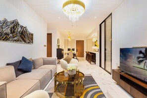 Ein modernes Wohnzimmer mit einer Couch, einem runden Couchtisch, einem Fernseher und einer Chandelier.