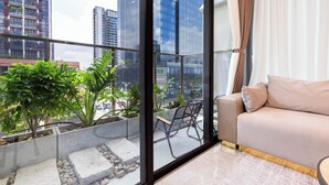 Ein modernes Wohnzimmer mit einer Couch, einer Bank und Blick auf eine Stadtlandschaft durch große Fenster.