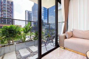 Ein modernes Wohnzimmer mit einer Couch, einer Bank und Blick auf eine Stadtlandschaft durch große Fenster.