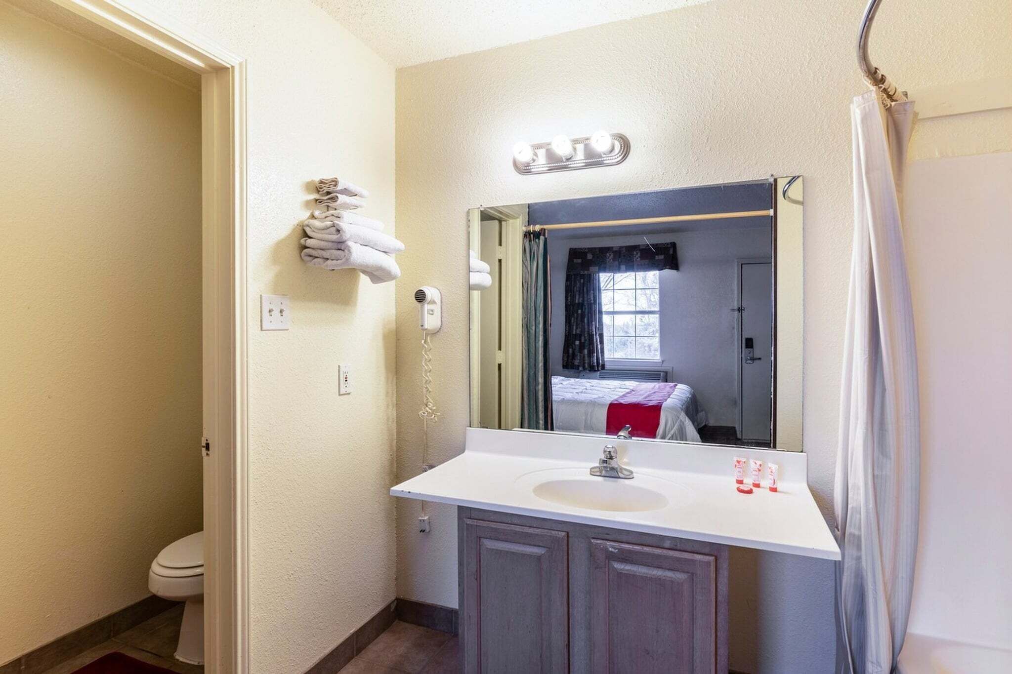 A bathroom with a white sink, a mirror, a towel rack, and a shower curtain.
