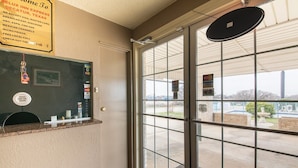 Ein Hotel-Empfangsbereich mit Glastür, einer Rezeption und einem Schild, das akzeptierte Zahlungsmittel wie American Express, MasterCard und Visa auflistet.