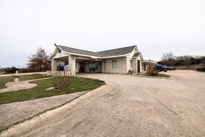 A two-story house with a garage, a driveway, and a small garden with a fountain.