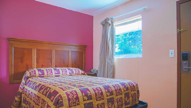 A room with a bed, a window with curtains, and a door. - Premium Queen Bed|Non-Smoking (Decatur GA)