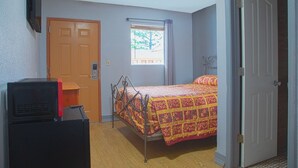 A bedroom with a bed, a door, a window, and a television.