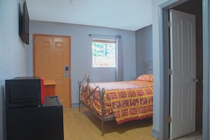 A bedroom with a bed, a door, a window, and a television. - Queen Bed|Non-Smoking (Decatur GA)