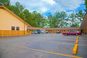 A parking lot with a yellow building, a red car, and a moving truck. - Queen Bed|Non-Smoking (Decatur GA)