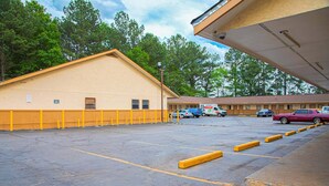 A motel with a large parking lot, a yellow building, and a covered area.