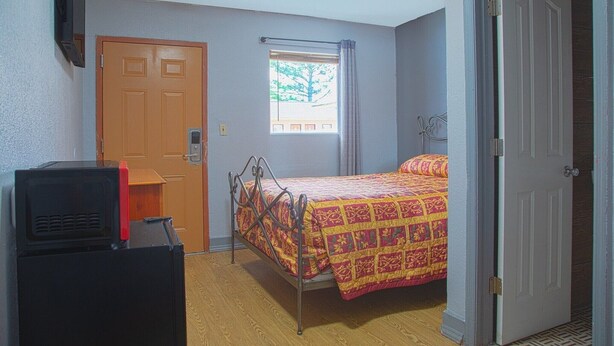 A bedroom with a bed, a door, a window, and a television.