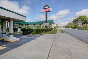 Un motel con un letrero OYO bien visible, un estacionamiento y una carretera al fondo.