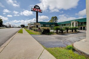 A hotel with a prominent OYO sign, a parking lot, and a building with a green roof. - Douglas GA | King Bed (Douglas GA)