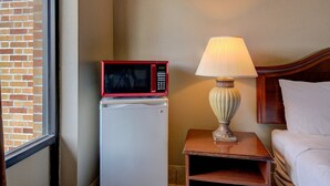 Ein Hotelzimmer mit einer Mikrowelle auf einem Kühlschrank, einer Nachttischlampe und einem Bett.