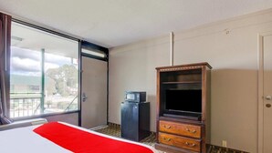 Ein Hotelzimmer mit einem Bett, einem Fernseher, einer Minibar und einer Schiebetür zum Außenbereich.