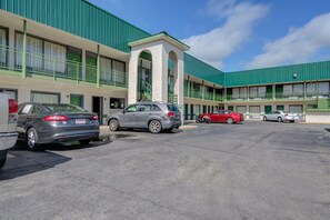A motel with a green facade, multiple parking spaces, and a central entrance with a small archway. - Douglas GA | King Bed (Douglas GA)