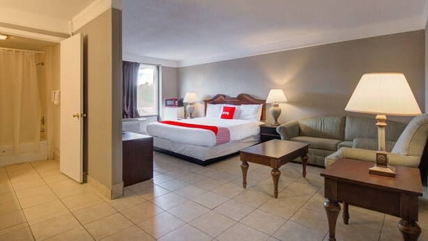 A hotel room with a bed, a sofa, a coffee table, and a lamp. - Premium King Bed|Douglas GA (Douglas GA)