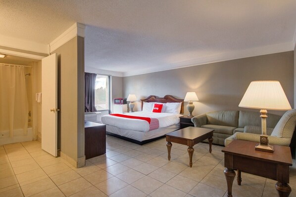 A hotel room with a bed, a sofa, a coffee table, and a lamp.