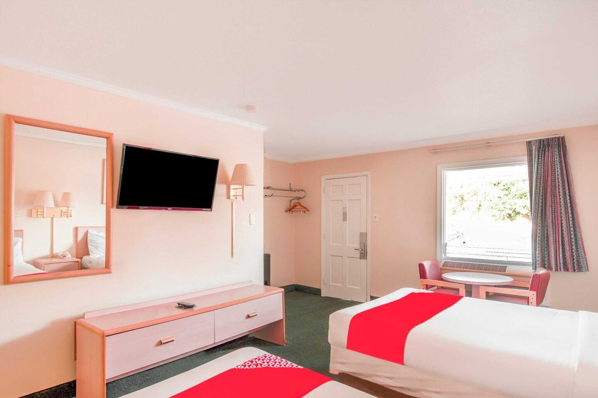 A hotel room with a bed, a TV, a desk, a chair, and a window.