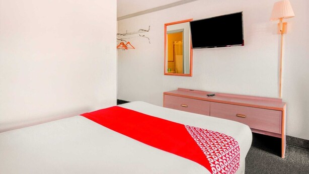 Una habitación de hotel con cama, cómoda, televisión y lámpara.