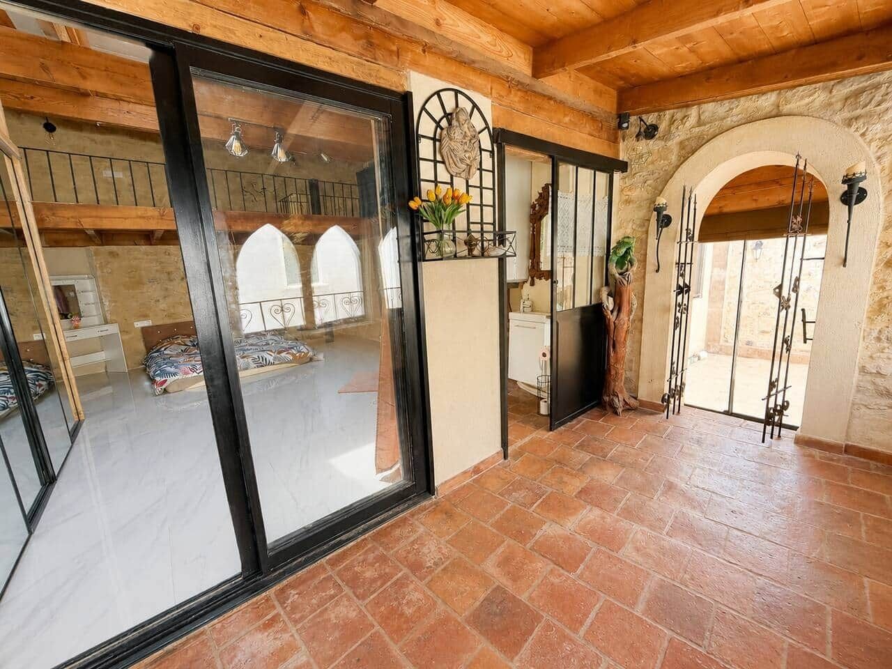 A spacious room with a large sliding glass door, a stone wall, and a rustic wooden ceiling.
