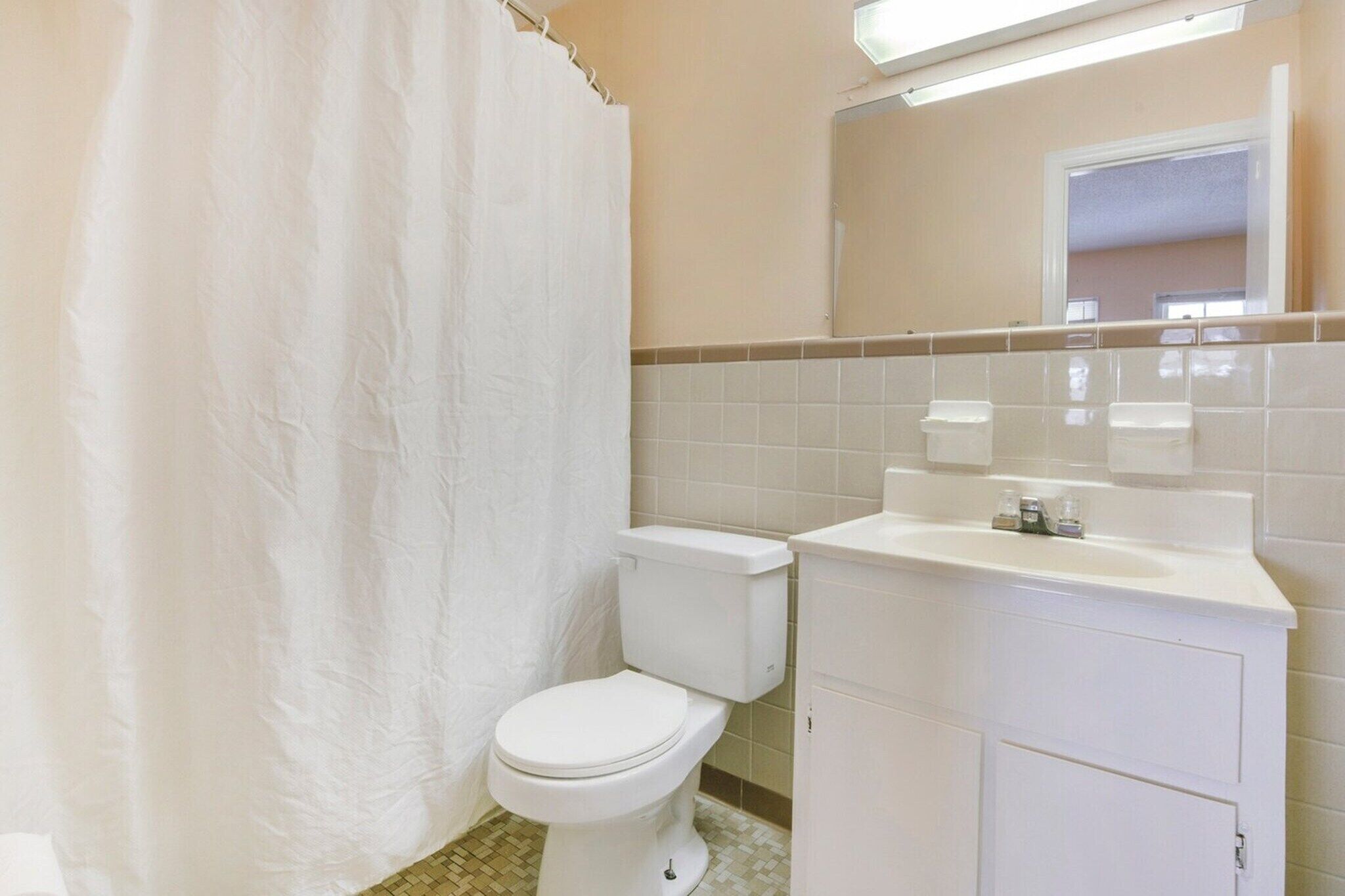 Un baño con inodoro, lavamanos y espejo.