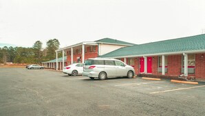 A motel with multiple rooms, a parking lot, and a green roof.