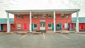 A two-story brick building with a sign reading 'OYO HOTEL' and a Coca-Cola vending machine.