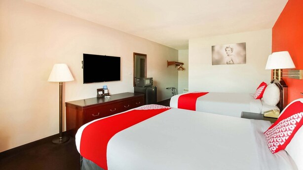 A hotel room with two beds, a flat-screen TV, a desk, a lamp, and a mirror. - Texarkana TX | 2 Full Bed (Texarkana TX)