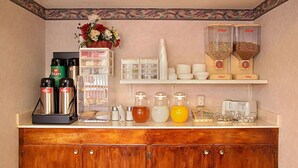 A kitchenette with a coffee maker, tea kettle, sugar and creamer dispensers, and a fruit bowl.