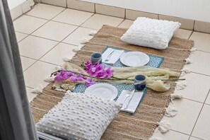 Une table dressée avec une nappe, des assiettes, des couverts et un set de table en fibres tressées.