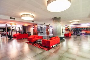 Un hall d’entrée spacieux, doté de sièges rouges, d’une grande colonne et d’un design de plafond moderne.