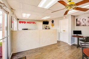 A hotel reception area with a reception desk, a ceiling fan, a clock, and a television. - King Bed | Smoking|Texarkana TX (Texarkana TX)