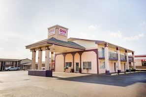 Un hotel con entrada cubierta, un letrero que dice 'OYO HOTEL' y un estacionamiento.