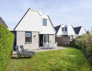 Ein modernes Haus mit Terrasse, Essbereich und kleinem Garten.