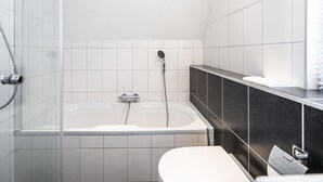 A modern bathroom with a bathtub, a shower, and a toilet. - Home With Dune Views in Zeeland (Vlissingen)