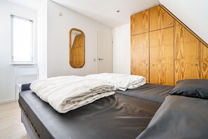 Ein Schlafzimmer mit einem Bett, einem Holzschrank, einem Spiegel und einem Fenster.