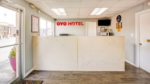 A hotel reception area with a marble reception desk, a clock, and a television on the wall.