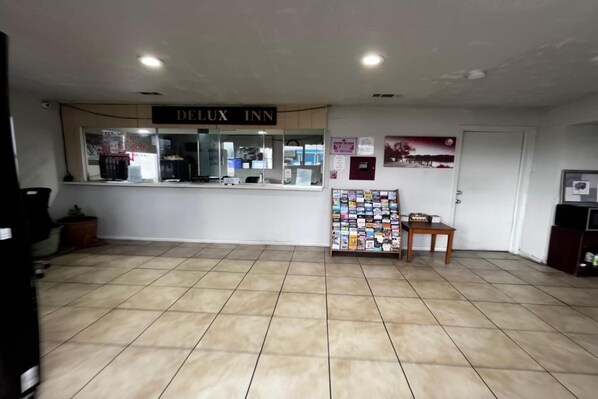 A hotel reception area with a 'Delux Inn' sign, a reception desk, a bulletin board, and a tiled floor.