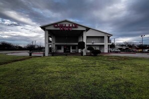 A DELUXE INN building with a flat roof, a central entrance, and a parking lot.