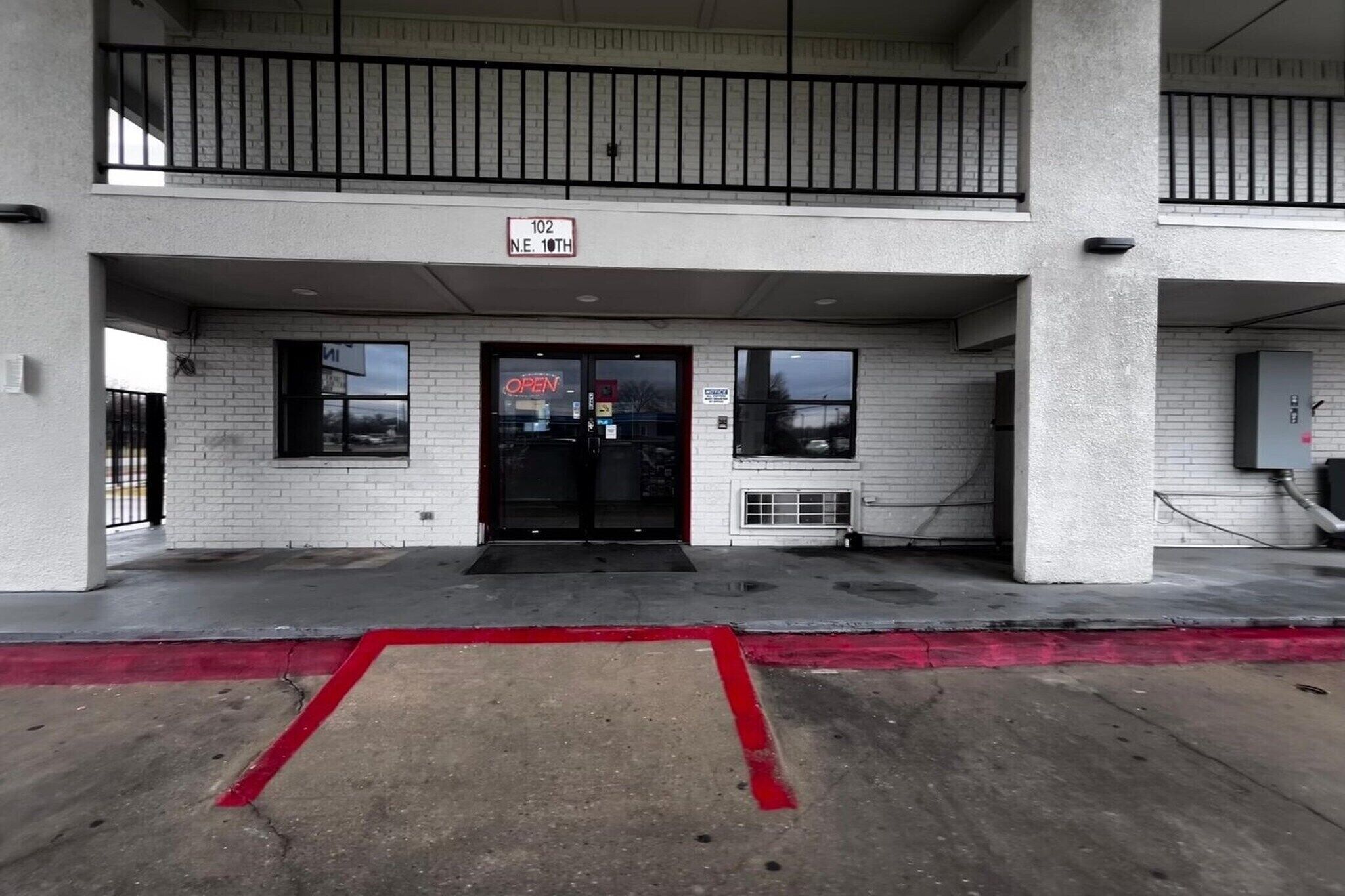 A building with a double entrance, a sign indicating '102 N.E. 10th,' and a red curb.