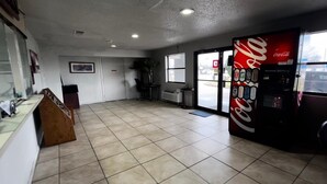 A clean, empty room with a Coca-Cola vending machine, a reception desk, and a large window.