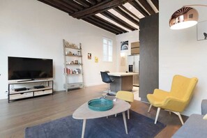 Ein modernes Wohnzimmer mit einem Flachbildfernseher, einem Couchtisch, einem gelben Sessel und einem Bücherregal.