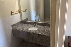 Ein Badezimmer mit einer Granittheke, einem weißen Waschbecken, einem Spiegel und einem Handtuchhalter.