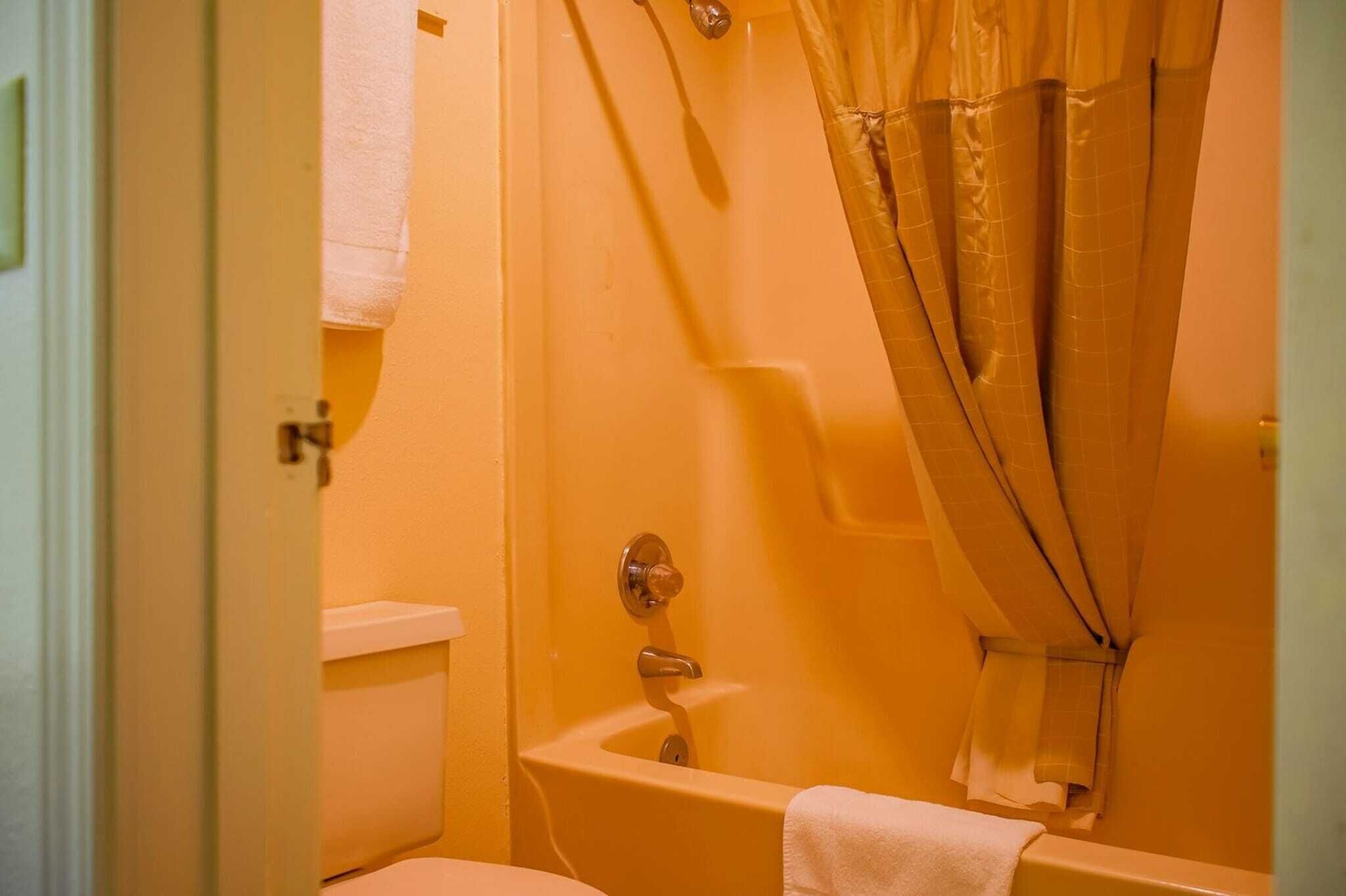 A bathroom with a bathtub, toilet, and a shower curtain.