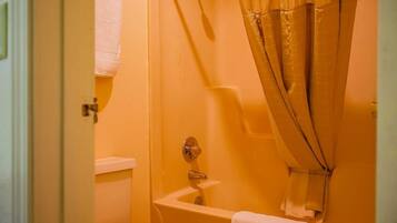 A bathroom with a bathtub, toilet, and a shower curtain.